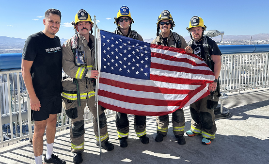 Firefighters pose with DLG Injury Law team member JC at the top of The STRAT Tower after completing the 1,455-step memorial climb